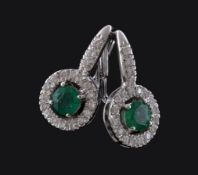 A pair of emerald and diamond earrings, the circular cut emeralds claw set within a surround of
