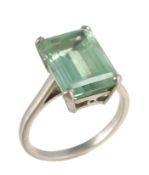 A green tourmaline dress ring, the step cut green tourmaline with canted corners, in a four claw