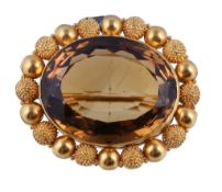 A mid Victorian citrine brooch, circa 1860, the oval cut citrine within a textured and polished
