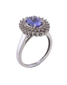 A tanzanite and diamond cluster ring, the central oval cut tanzanite claw set within a surround of