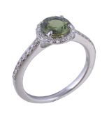 A green sapphire and diamond cluster ring, the circular cut green sapphire within a surround of
