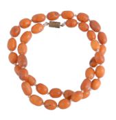 An amber bead necklace, composed of oval amber beads, on a knotted string, 56.5cm long