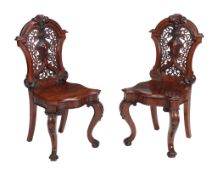 A pair of Victorian mahogany hall chairs, circa 1870, each cartouche back with pierced decoration