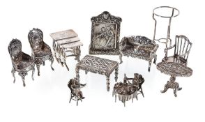 A collection of silver and silver coloured miniature furniture, including: two cherubs sat eating