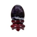 A Blue John egg ornament, the polished Blue John of ovoid form, sitting in a wooden stand, egg