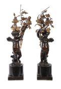 A pair of patinated and parcel gilt bronze twin light figural candelabra, circa 1900, each modelled