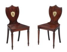 A pair of mahogany hall chairs , circa 1825 and later painted, each cartouche back with central