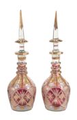 A pair of Bohemian/Czech clear, ruby-flashed and enamelled glass large bottles and spire stoppers