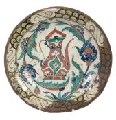 An Iznik dish, circa 1600, of shallow rounded form on a short foot with everted rim, decorated in