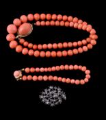 Ω A coral necklace, composed of graduating polished coral beads, to a coral set oval clasp, stamped