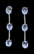 A pair of aquamarine and diamond earrings, each set with three oval cut aquamarines claw set with