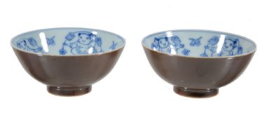 A pair of Chinese bowls, the interiors painted with blue and white with dancing figures, the