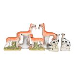 A pair of Staffordshire pottery models of greyhounds with hares, 19th century, 28cm high; another