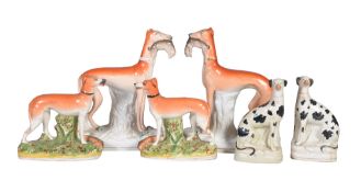 A pair of Staffordshire pottery models of greyhounds with hares, 19th century, 28cm high; another