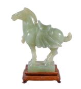 A Chinese celadon jadeite horse , in archaic style, standing with saddle, 16.8cm high, wood stand