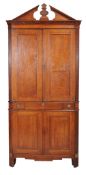 A French oak corner cabinet, 19th century, the panel doors enclosing shelves, above three frieze