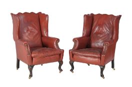 A pair of red leather upholstered wing armchairs, early 20th century, of slightly differing sizes