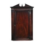 A George III mahogany hanging corner cupboard, circa 1760, the arched pediment above a blind fret