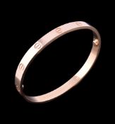 An 18 carat gold 'Love' bangle by Cartier, the polished bracelet with screw detail, signed Cartier,