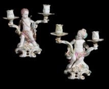A pair of Chelsea figural two-branch candelabra , circa 1765, each modelled with a seated putto on