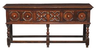A Charles II oak dresser base, circa 1660, the plank top with moulded edge, above three mitre