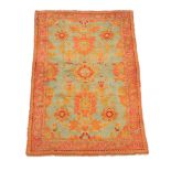 An Ushak rug, the green field decorated with varying medallions, within a madder and orange