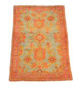 An Ushak rug, the green field decorated with varying medallions, within a madder and orange
