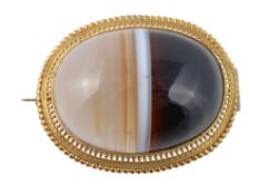 A Victorian banded onyx brooch, circa 1880, the oval cabochon banded onyx within a bead work