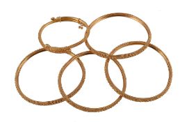 Four bangles, with heart and bead detail, 5.7cm inner diameter; and a smaller similar bangle, 4cm