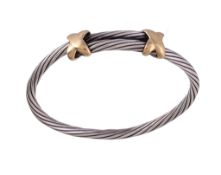 A silver and gold sprung bangle , the twisted silver bangle with gold cross shaped terminals, with