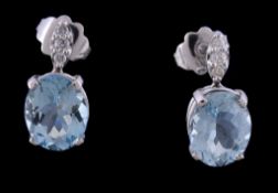 A pair of aquamarine and diamond earrings, the oval cut aquamarine in a four claw setting, below a
