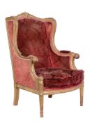 A giltwood wing armchair in Louis XVI style , early 20th century, with crimson damask velvet