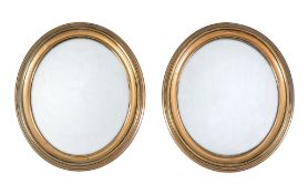 A pair of oval gilt brass wall mirrors, late 19th/ early 20th century, each 44cm high, 38cm wide