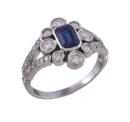 A sapphire and diamond flower head cluster ring, the step cut sapphire with canted corners, within a