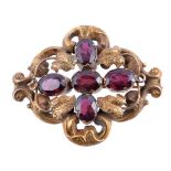 An early Victorian garnet brooch, circa 1850, the scrolled foliate panel set with oval cut