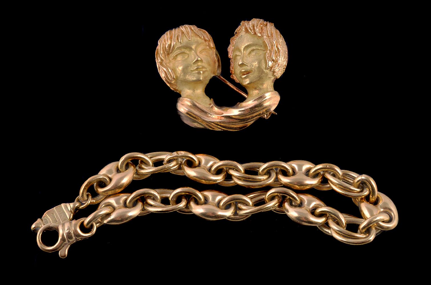 A novelty gold coloured brooch, cast as the profiles of two conversing people, with textured hair,