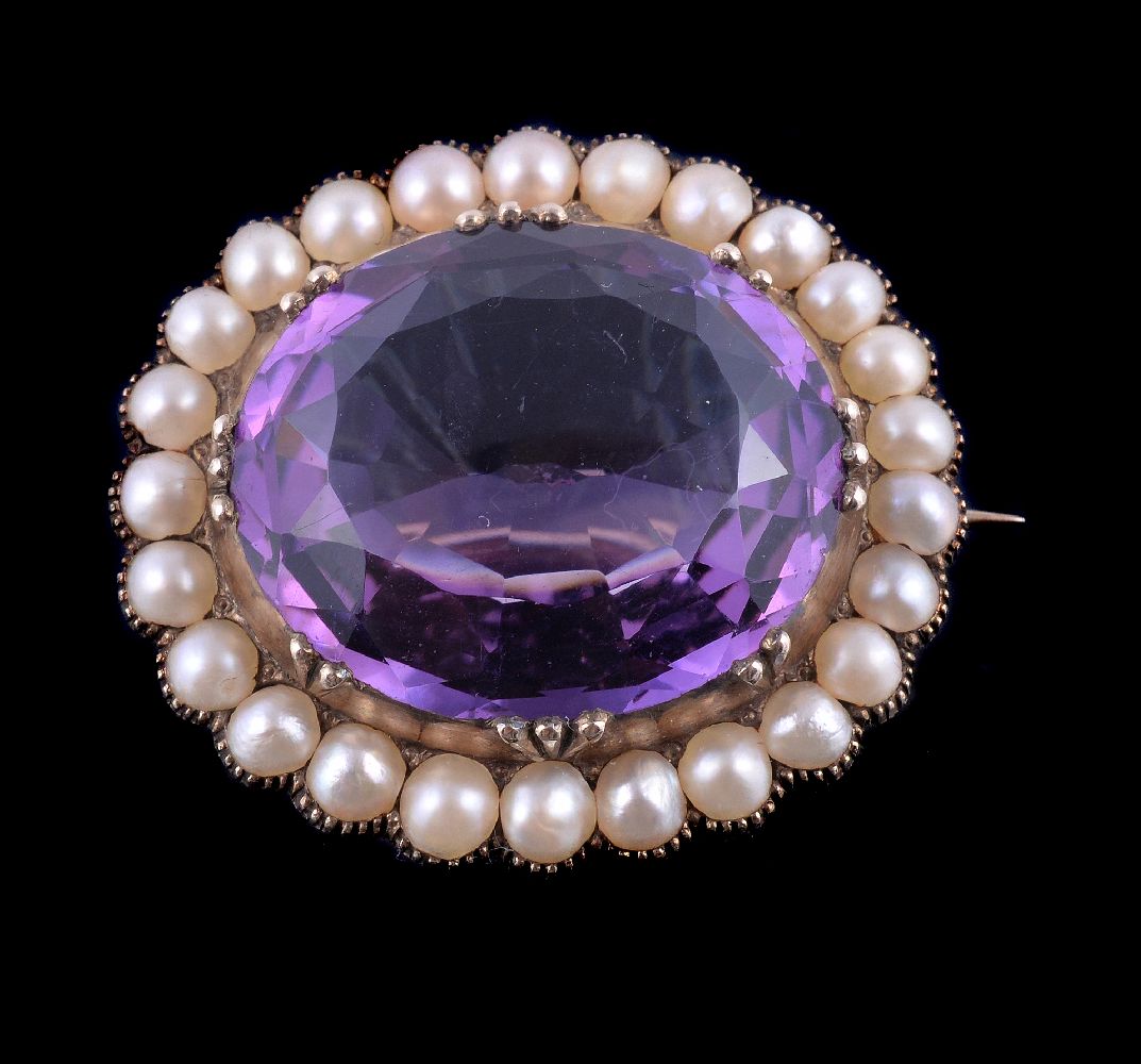 An Edwardian amethyst and half pearl brooch, the oval cut amethyst in a collet setting, within a