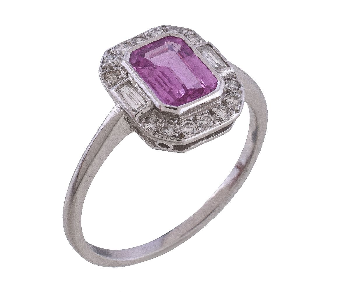 A pink sapphire and diamond cluster ring, the step cut pink sapphire with canted corners, within a