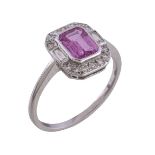 A pink sapphire and diamond cluster ring, the step cut pink sapphire with canted corners, within a