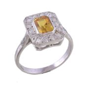 A yellow sapphire and diamond cluster ring, the step cut yellow sapphire within a surround of