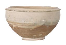 A Chinese 'Cizhou' deep bowl, Song Dynasty, raised on a short foot with milled rim, the cream