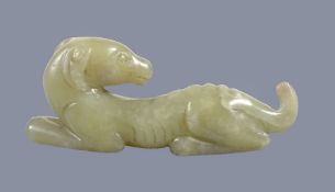 A Chinese yellow jade carving of a hound, recumbent with head turned back, with some natural