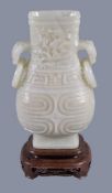 A Chinese white jade vase, hu, the pear-shaped vessel quartered on each side by high strapwork
