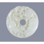 A Chinese white jade 'Buddhist Lion' disc, bi, of even pale tone, carved with two lions chasing a