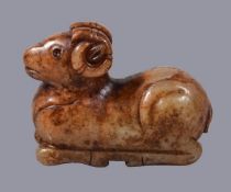 A Chinese celadon and russet jade figure of a ram, recumbent, with head looking forwards and its
