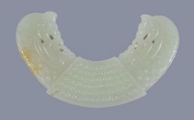 A Chinese archaistic white and russet jade pendant, Huang, the arc-shaped pendant carved in low