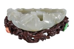A Chinese white jade brush washer, with minor russet inclusions, carved in the form of a lotus leaf,