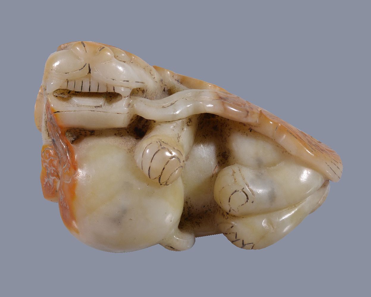 A Chinese white and russet jade Buddhist lion, with incised details, the mouth slightly opened