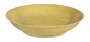 An Imperial style yellow-glazed dish, the shallow rounded sides supported on a tapered foot, covered