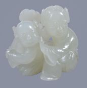 A small white jade group of a mother and child, both seated with the child holding a ruyi sceptre,
